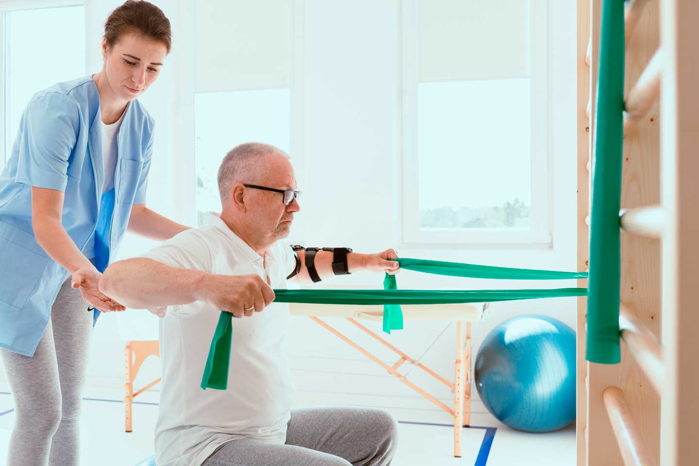 Exercício com banda elástica acompanhado por uma fisioterapeuta, em Pilates Clínico